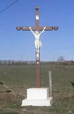 Photographie en couleurs d'un monument en bois et pierre représentant une Crucifixion.