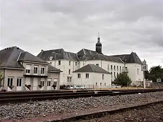 Photographie en couleurs d'un ensemble de bâtiments dont les toits en ardoise sont surmontés d'un clocheton.