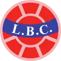 Logo rond avec l'inscription « LBC » sur un bandeau bleu clair au centre d'un ballon de football rouge-orange.