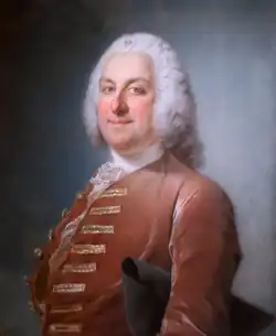 Portrait en buste d’un homme portant perruque, avec veste de velours rouge et tricorne sous le bras gauche.