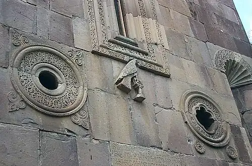 Détail de la façade sud : les deux oculi, la fenêtre centrale, une colombe sur un perchoir et la partie supérieure d'une des niches.