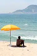Homme sous un parasol de plage entoilé et repliable.