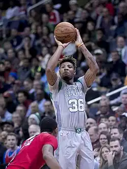 Un joueur de basket-ball saute balle au main et s'apprête à le lancer vers le panier.