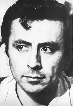 Portrait noir et blanc d'un homme brun, de face regardant vers la droite.