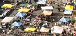 Marché vu de dessus, avec des stands et des parasols de plusieurs couleurs.