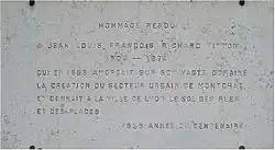 Plaque commémorant grise avec texte gravé en lettres capitales.