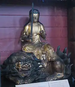 photo d'une statue japonaise en bronze du bodhisattva de Manjusri, portant une épée et assis sur un lion menaçant