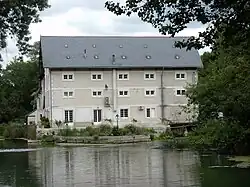 Photographie en couleurs d'un long bâtiment à plusieurs étages établi au-dessus d'un cours d'eau.