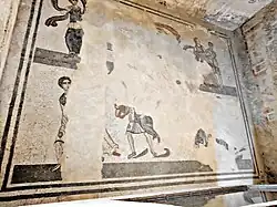 Photo : vue d'un sol en mosaïque où ne subsistent que les fragments d'une danseuse et de 2 couples dansants.