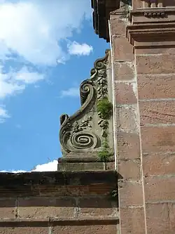 Volute en pierre blanche sur un portail en grès rose du XVIIIe&nbsp;siècle (abbaye de Moyenmoutier, Vosges.
