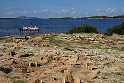 Vue d'un site archéologique au bord de la mer avec un bateau touristique à l'arrière-plan