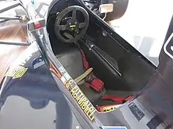 Photo du cockpit de la Minardi M191B, avec le volant et le harnais de sécurité