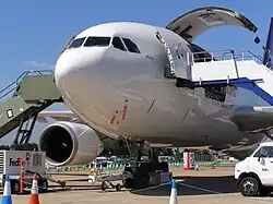 Avion au sol. Une grande porte cargo est ouverte du côté gauche.