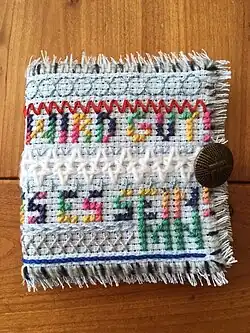 Porte-aiguilles avec un texte brodé au point de croix