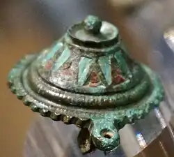 Petit objet circulaire en métal tirant sur le vert.