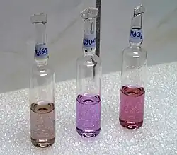 Composés du néodyme en lumière de tube fluorescent - de gauche à droite, le sulfate, le nitrate et le chlorure