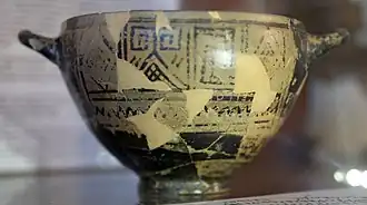« Coupe de Nestor », du côté de l'inscription, v. 720 av. J.-C., musée archéologique de Pithécusses (haut) et transcription de l'inscription avec la reconstitution des passages perdus (bas). Traduction : « Agréable est de boire dans la coupe de Nestor, mais quiconque boit de cette coupe est aussitôt saisi du désir d'Aphrodite à la belle couronne. »