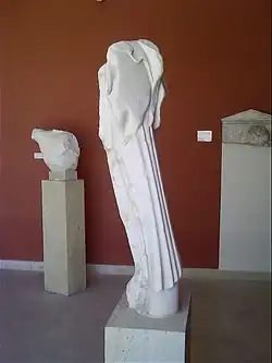 Statue de Niké (A245), de dos. Marbre de Paros, 480 - 470 av. J.-C. Au fond, torse d'hoplite (A756) (480 av. J.-C.) et stèle funéraire (milieu du Ve&nbsp;siècle&nbsp;av. J.-C.).
