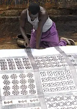 Utilisation d'un peigne pour tracer des lignes parallèles sur un tissu adinkra à Ntonso, Ghana.