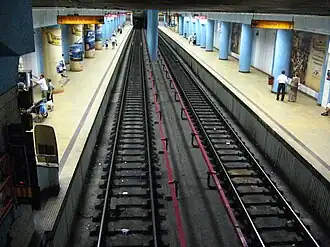au centre les deux voies encadrées par deux quai latéraux avec des poteaux de soutien ronds et peints en bleu.