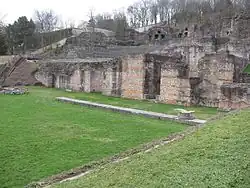 Vestige du portique avec son stylobate et une base de colonne. Le dallage du portique est couvert d’un gazon de protection.