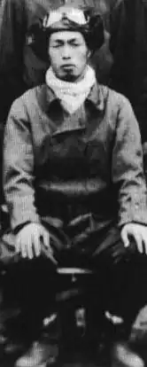 Photo noir et blanc d'un pilote en combinaison de vol, assis.