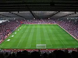 Pelouse verte tondue dans la longueur dans un stade rempli de spectateurs.