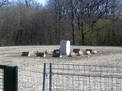 Photographie en couleurs d'une petite construction au centre d'une grande aire gravillonnée.
