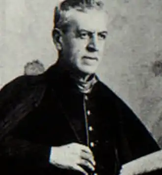 photo noir et blanc d'unprêtre d'environ soixante ans, assis avec un livre