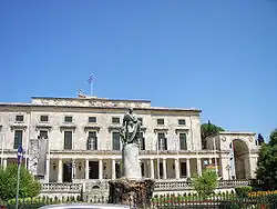 Grand bâtiment à péristyle devant lequel se trouve une statue de bronze