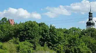 L'église et la tour de la mairie au-dessus des arbres sur la Parthe