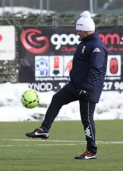 Photographie montrant Pascal Dupraz habillé d'un survêtement bleu et d'un bonnet blanc jonglant avec un ballon sur une pelouse