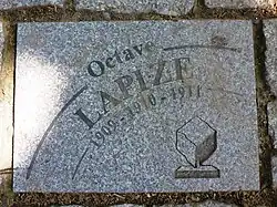 Photographie d'un pavé gris portant l'inscription « Octave Lapize 1909-1910-1911 ».