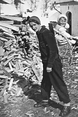 Greti Caprez-Roffler portant son enfant sur le dos au moyen d'une chaise portable.