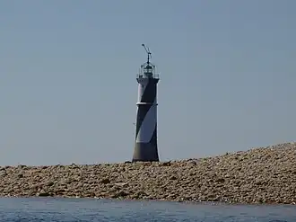 Vue d’un phare en arrière-plan d’une plage, le corps blanc et noir.