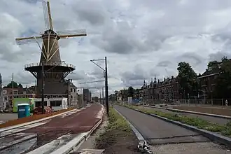 Photographie en couleurs d'un moulin à vent entouré d'un paysage urbain en travaux.