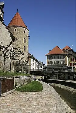 photographie en couleurs d'une partie des douves d'un château, de son enceinte et d'une des tours qui la flanquent.