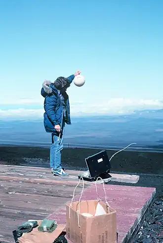 Le même homme tient la fiole au-dessus de sa tête, les bras tendus.