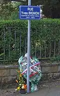Gerbe de fleurs posée devant le nouveau panneau de la rue Yves-Bignon