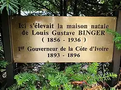 Plaque en laiton dans la haie de tuyas qui entoure la maison natale de Louis-Gustave Binger.