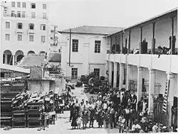 photographie noir et blanc : une foule devant un portique à deux étages