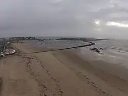 Le port d'échouage est aménagé sur la partie orientale de la plage des Libraires, en survol de laquelle est pris ce cliché. En arrière-plan, à droite, le port en eaux profondes, relié à la pointe du Bec par un viaduc. (Vue hivernale).