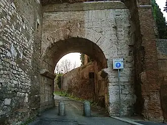 Photographie en couleurs d'une arche en pierre au-dessus d'une rue.