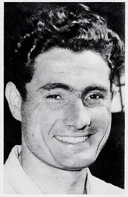 Photo en noir et blanc d'un homme souriant aux cheveux noirs.