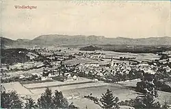 Aerial photograph of a small town surrounded by mountains and agricultural fields.