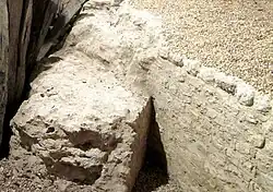 Vue d'une portion de mur arasé se raccordant à un autre mur courbe