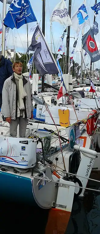 debout à l'arrière de son voilier, au ponton