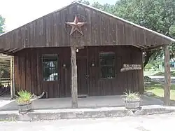 Photo d'un bâtiment rustique, en bois. Le porche est surmonté d'une grande étoile.