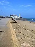 Vue des vestiges du rempart maritime ; au fond, le borj as-Sirat et le phare