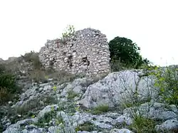 Un bout de mur en petites pierres, ruiné, construit au-dessus d'un bloc rocheux